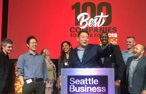 a man stands at a podium pointing in the distance smiling