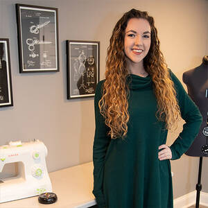 photo of woman in green turtleneck with long wavy blonde hair smiling at the camera